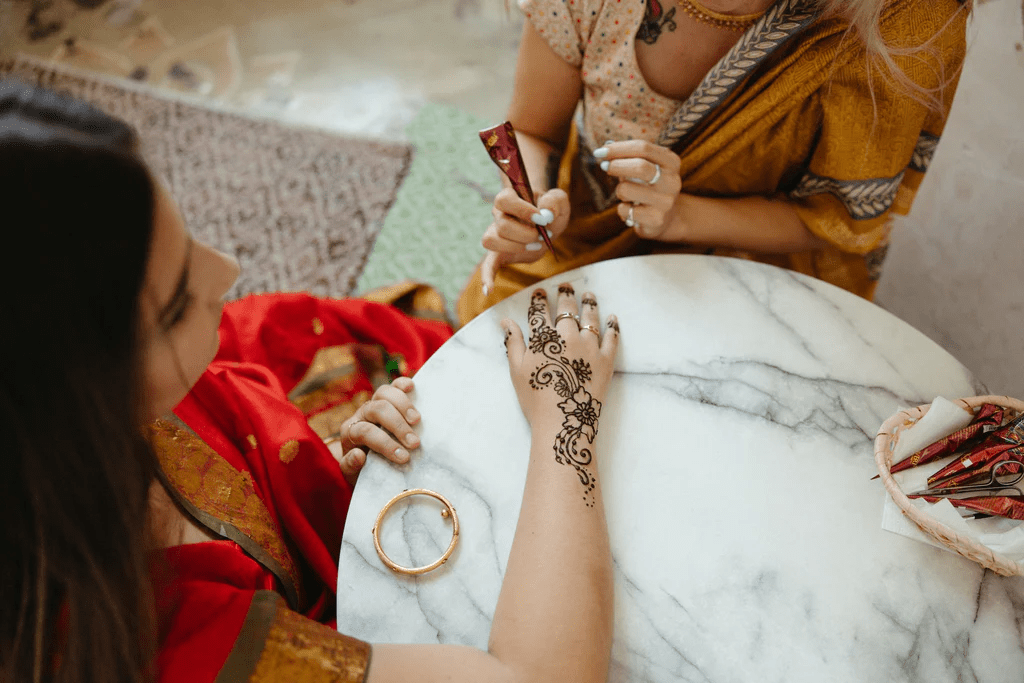 Woman applying intricate mehndi design on hand for rich colour and smooth finish